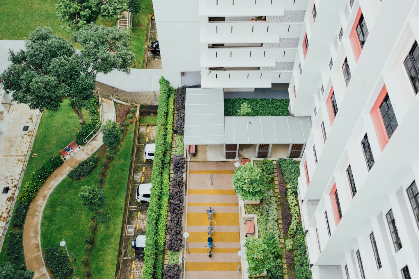 White buildings with coral accents surrounded by green lawns and gardens.