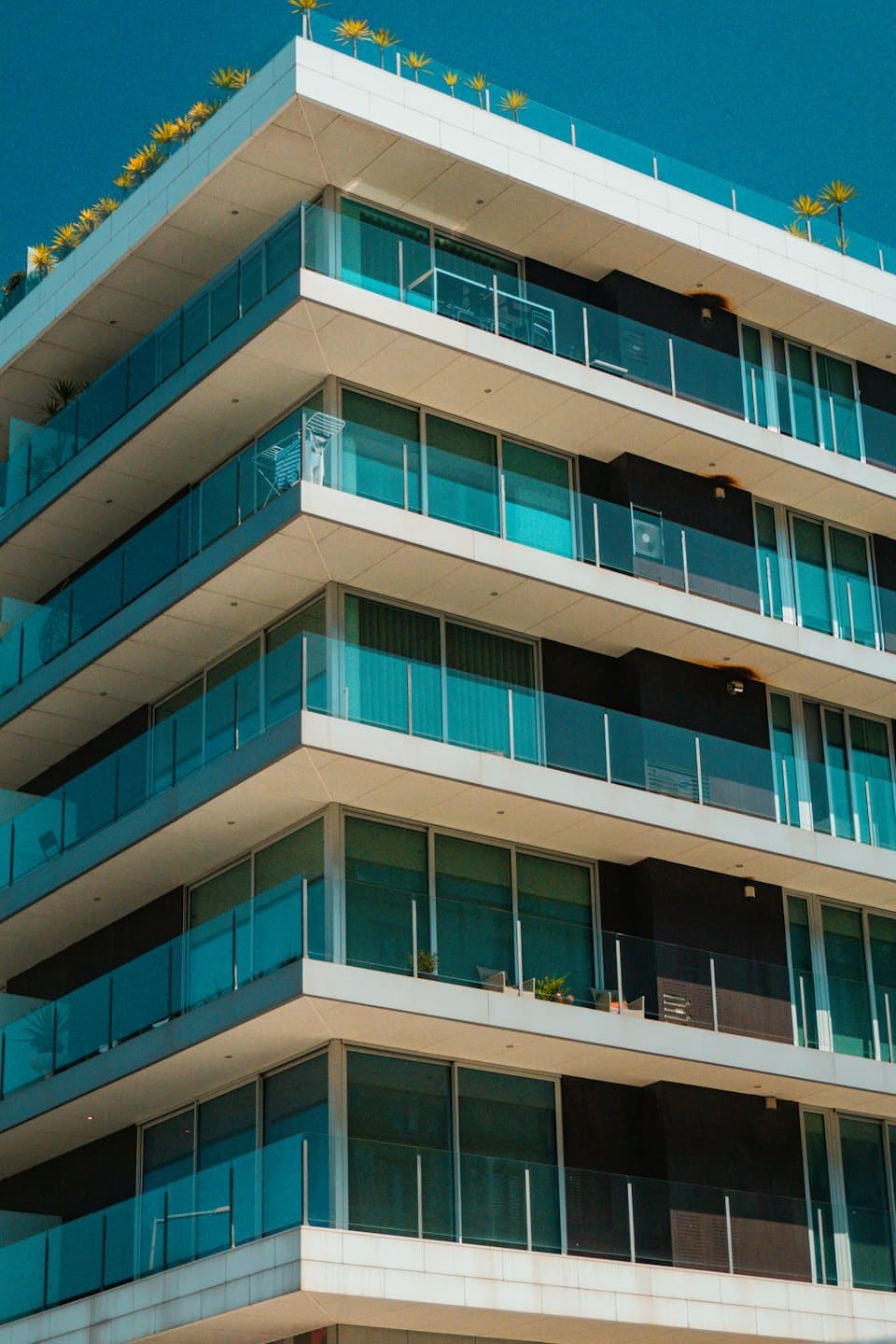 Modern apartment building with white and grey facade and teal windows.